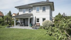 Die Stadtvilla Verona mit überdachter Terrasse. Auf dem Grundstück standen vorher mehrere Bäume, die weichen mussten. Jetzt haben die Horstmeyers viel Platz zum Grillen und das Töchterchen zum Spielen. Foto: Roth-Massivhaus / Gerhard Zwickert