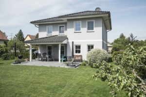 Die Stadtvilla Verona mit überdachter Terrasse. Auf dem Grundstück standen vorher mehrere Bäume, die weichen mussten. Jetzt haben die Horstmeyers viel Platz zum Grillen und das Töchterchen zum Spielen. Foto: Roth-Massivhaus / Gerhard Zwickert