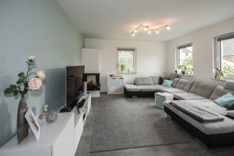 Der Kamin im Wohnzimmer verspricht Gemütlichkeit. Die zahlreichen Fensterelemente im Wohnbereich lassen viel Licht hinein. Foto: Roth-Massivhaus / Gerhard Zwickert