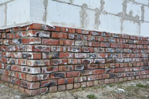 Mineralische Ausblühungen an der Grundmauer des Ziegelhauses.