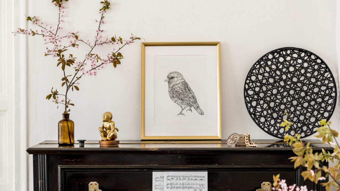 Stilvolle Komposition aus verschiedenen Dekoelementen im Wohnzimmer mit Plakatrahmen, getrockneten Blumen, Dekoration und eleganten Accessoires im modernen Wohnstil